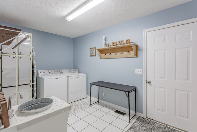 laundry area with light tile patterned flooring, washer and clothes dryer, and a textured ceiling