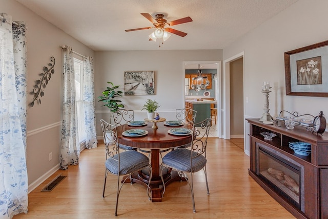 dining area featuring ceiling fan, a textured ceiling, and light wood-type flooring