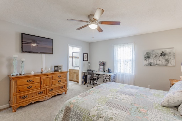 bedroom featuring ceiling fan, light colored carpet, connected bathroom, and a textured ceiling