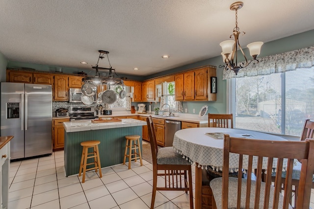 kitchen featuring a kitchen bar, stainless steel appliances, hanging light fixtures, and a kitchen island