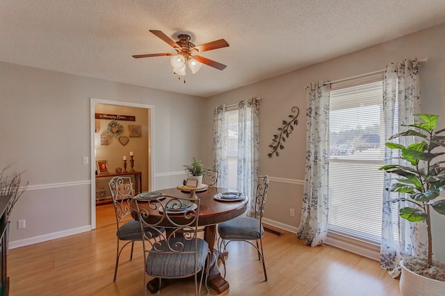 dining room featuring ceiling fan, plenty of natural light, light hardwood / wood-style floors, and a textured ceiling