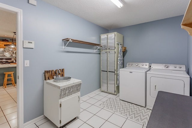 laundry room with light tile patterned floors, sink, independent washer and dryer, and a textured ceiling