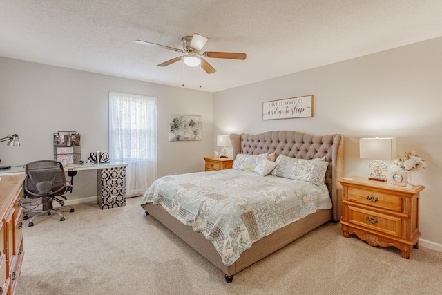 carpeted bedroom featuring ceiling fan and a textured ceiling