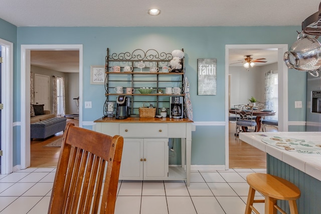 kitchen with white cabinetry, light tile patterned floors, tile counters, and a textured ceiling