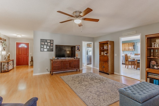 living room featuring ceiling fan, a textured ceiling, and light hardwood / wood-style flooring