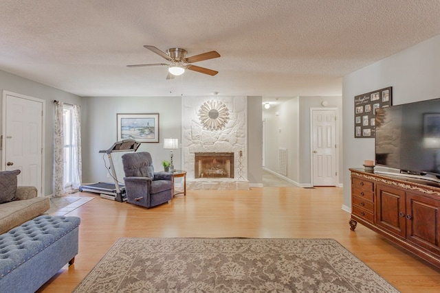 living room with a fireplace, a textured ceiling, and light wood-type flooring