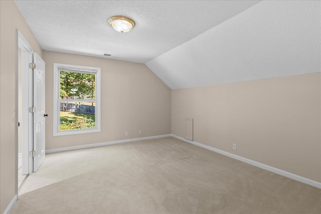 bonus room with light carpet, lofted ceiling, and a textured ceiling