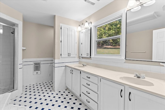 bathroom with heating unit, vanity, a shower with door, and tile walls