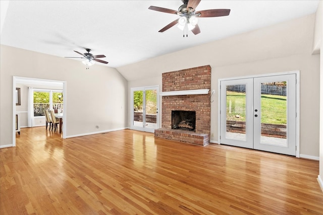 unfurnished living room featuring french doors, a fireplace, vaulted ceiling, and light wood-type flooring