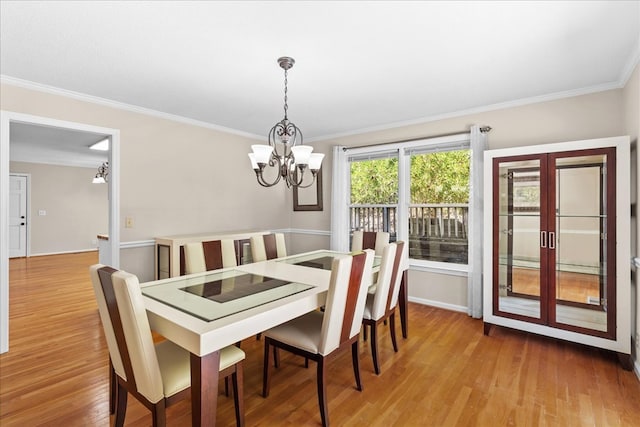 dining area featuring hardwood / wood-style flooring, crown molding, a chandelier, and french doors