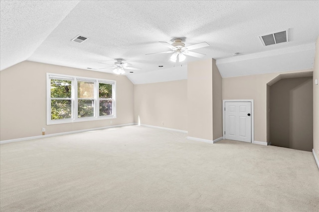 bonus room featuring lofted ceiling, light colored carpet, and a textured ceiling