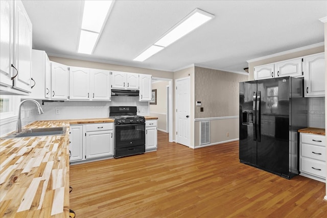 kitchen featuring butcher block countertops, sink, white cabinetry, black appliances, and light wood-type flooring