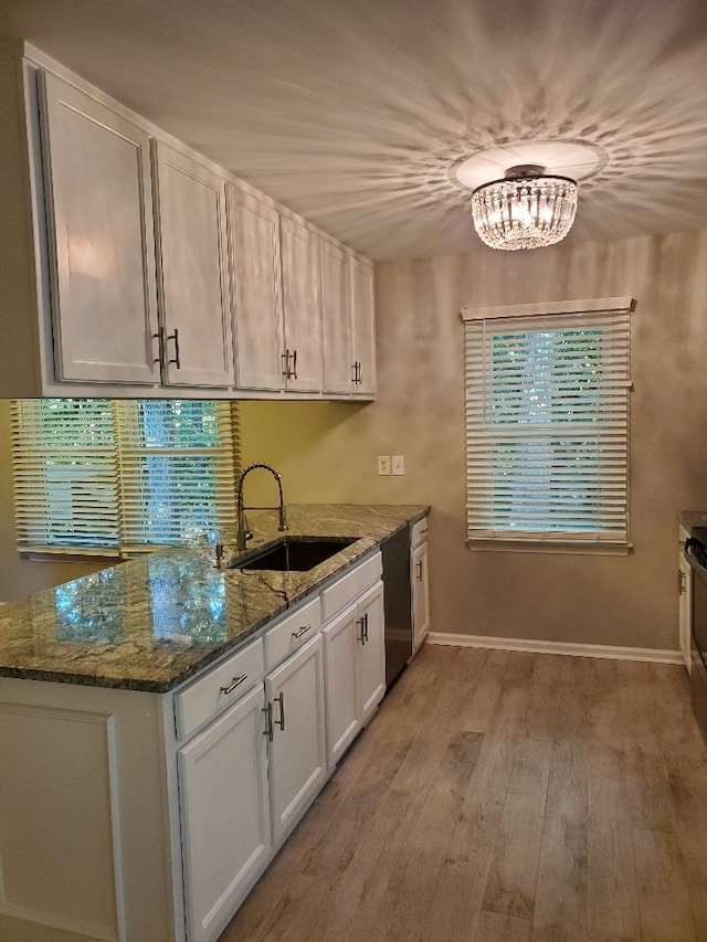 kitchen with sink, white cabinetry, stone countertops, light hardwood / wood-style flooring, and dishwashing machine