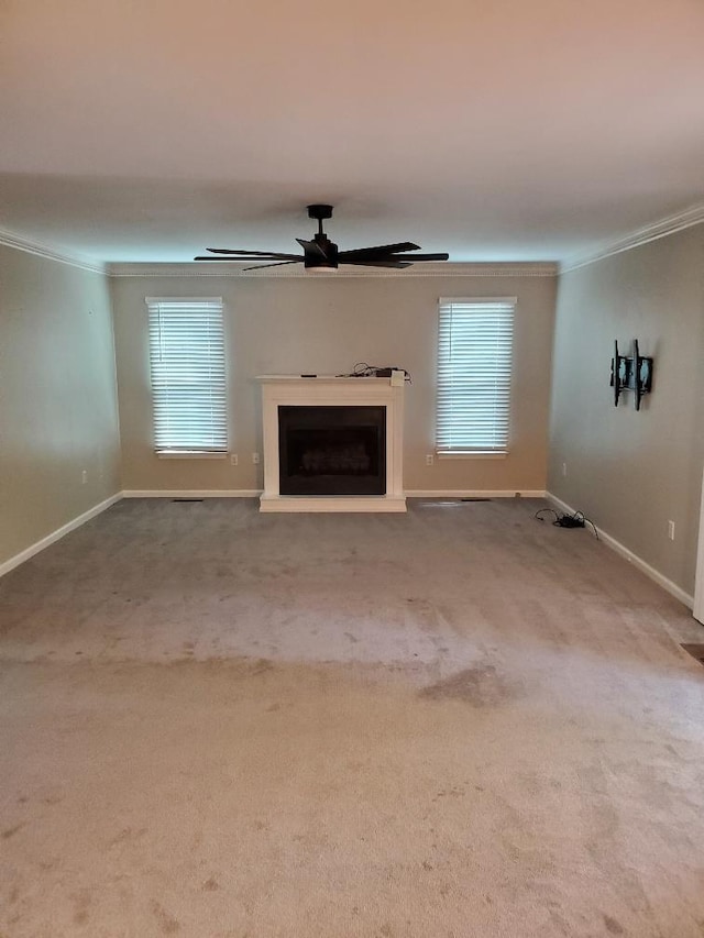 unfurnished living room featuring carpet floors, ornamental molding, and ceiling fan