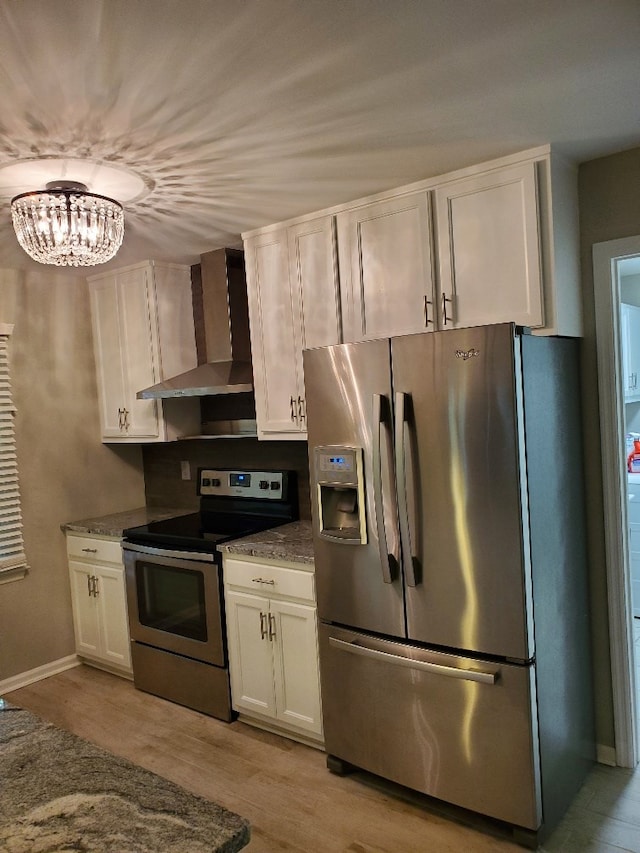 kitchen featuring stone countertops, white cabinetry, light hardwood / wood-style floors, stainless steel appliances, and wall chimney range hood