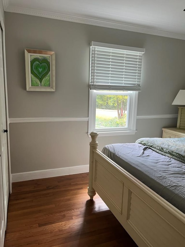 bedroom with ornamental molding and dark hardwood / wood-style floors