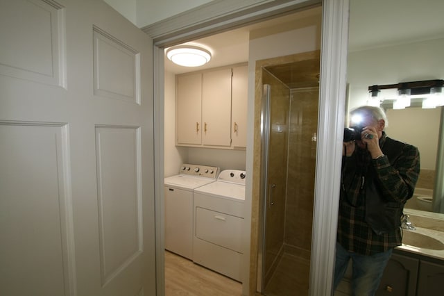 washroom with cabinets, sink, washer and clothes dryer, and light hardwood / wood-style floors