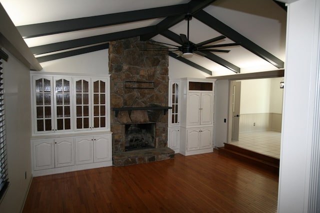 unfurnished living room featuring dark hardwood / wood-style flooring, a fireplace, lofted ceiling with beams, and ceiling fan