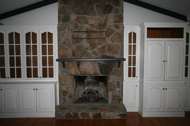 unfurnished living room featuring lofted ceiling, a stone fireplace, and dark wood-type flooring