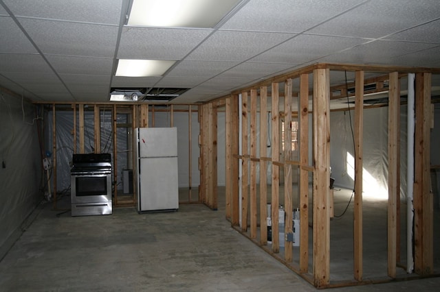 basement with white refrigerator and a drop ceiling