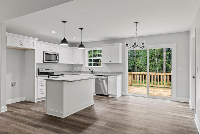 kitchen featuring stainless steel appliances, hanging light fixtures, and white cabinets