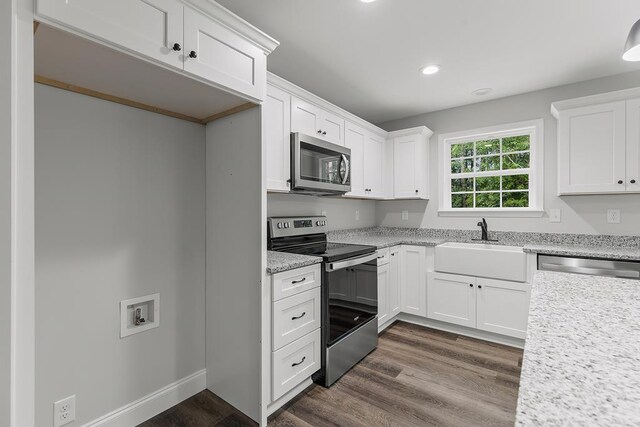 kitchen with white cabinetry, appliances with stainless steel finishes, light stone countertops, and sink