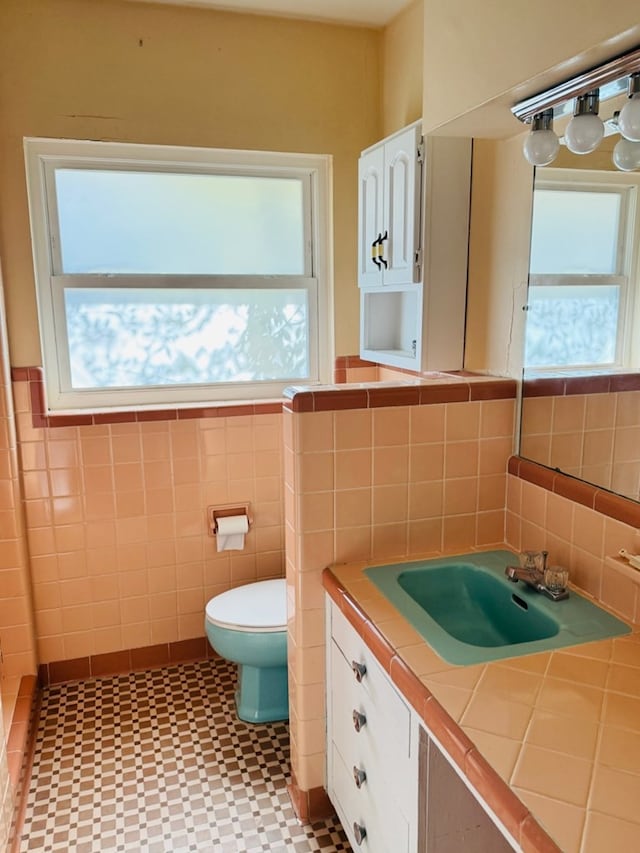 bathroom with vanity, tile walls, and toilet