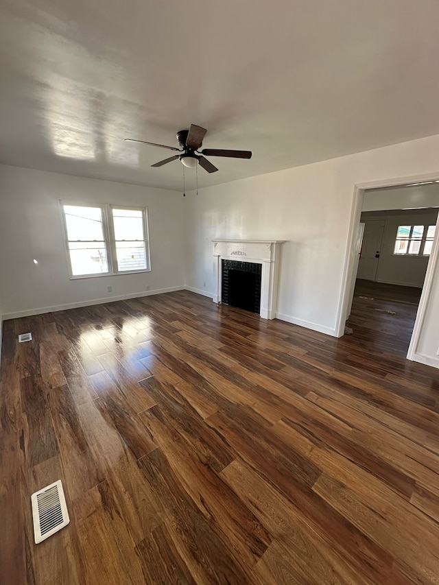 unfurnished living room featuring dark wood-type flooring and ceiling fan