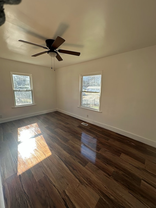 empty room with dark hardwood / wood-style flooring, plenty of natural light, and ceiling fan