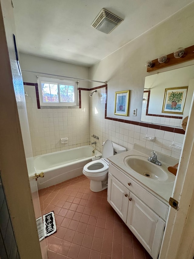 full bathroom featuring tile walls, tiled shower / bath combo, vanity, tile patterned floors, and toilet