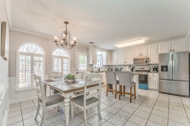 dining area featuring a textured ceiling, a chandelier, ornamental molding, healthy amount of natural light, and light tile patterned floors