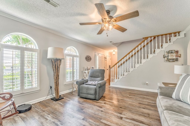 living room with crown molding, stairway, wood finished floors, ceiling fan, and a textured ceiling