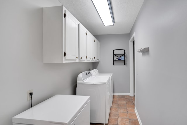 laundry room with washer and dryer, cabinets, and a textured ceiling