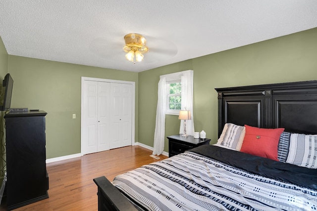 bedroom with ceiling fan, wood-type flooring, a closet, and a textured ceiling