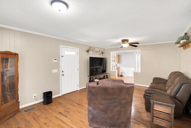 living room with ornamental molding, light hardwood / wood-style floors, and a textured ceiling