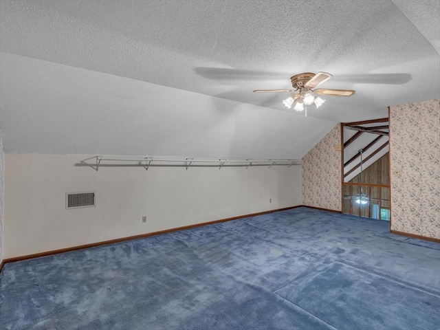 additional living space with vaulted ceiling, carpet flooring, ceiling fan, baseboards, and a textured ceiling