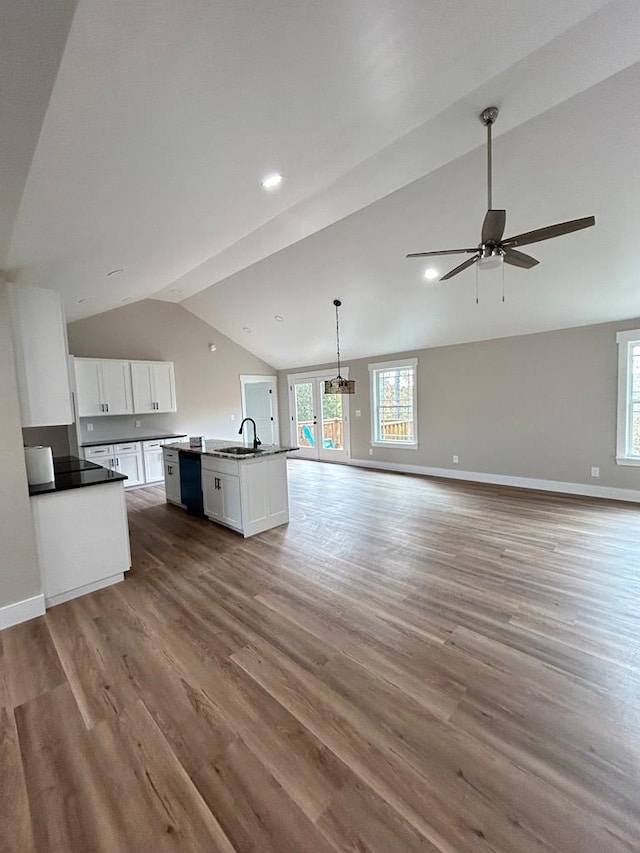 kitchen with vaulted ceiling, white cabinetry, black dishwasher, sink, and a center island with sink