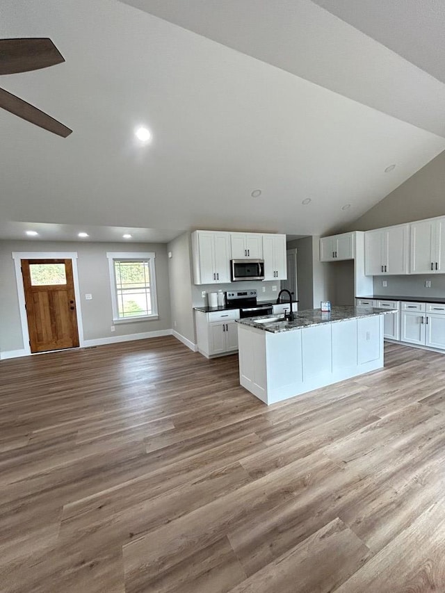 kitchen with stainless steel appliances, white cabinetry, an island with sink, and light hardwood / wood-style floors