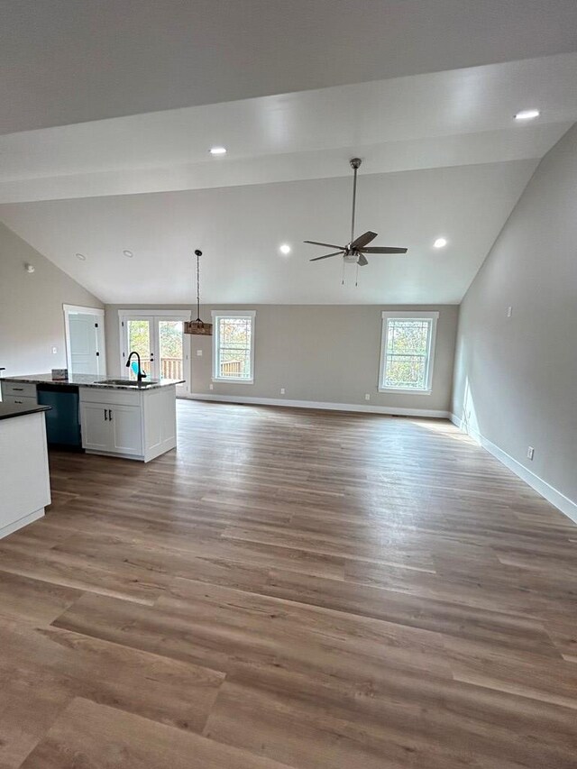 unfurnished living room with lofted ceiling, sink, hardwood / wood-style flooring, and a wealth of natural light