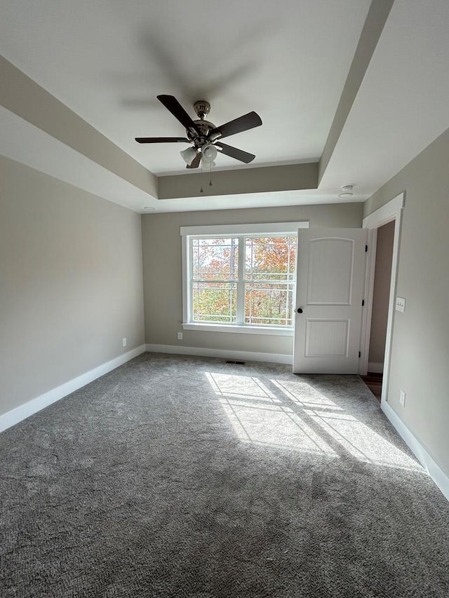 spare room featuring carpet floors, a raised ceiling, and ceiling fan