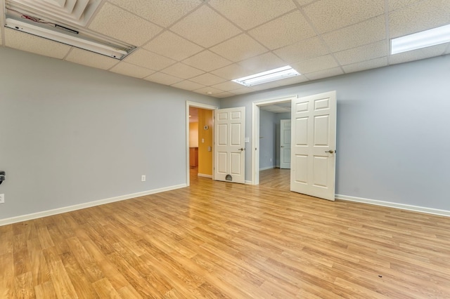 spare room with a drop ceiling and light hardwood / wood-style floors