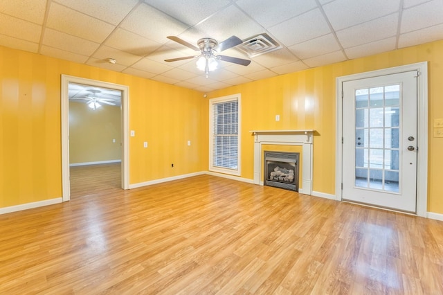 unfurnished living room featuring a drop ceiling, ceiling fan, and light wood-type flooring