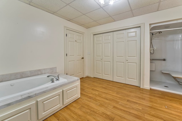 bathroom featuring a drop ceiling, hardwood / wood-style floors, and a washtub