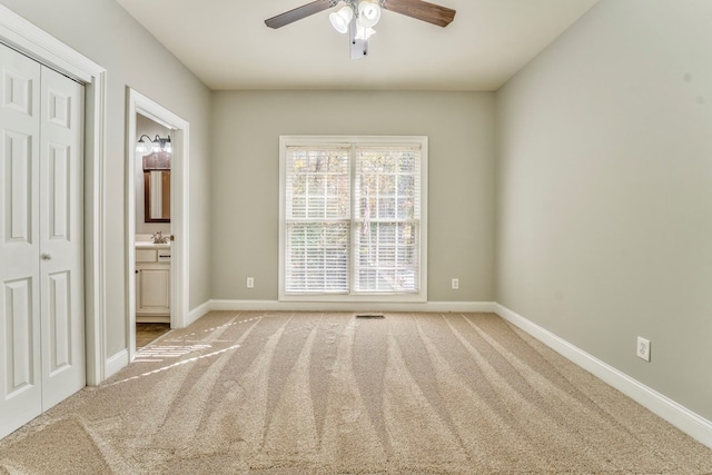 unfurnished bedroom with ensuite bathroom, carpet floors, and ceiling fan