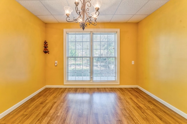 spare room featuring hardwood / wood-style flooring, a paneled ceiling, and an inviting chandelier