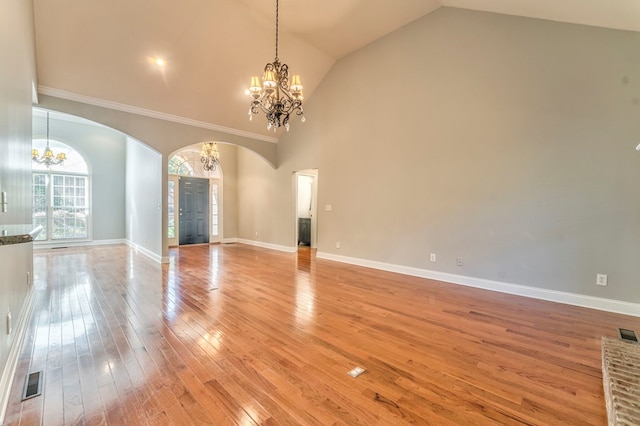 unfurnished living room featuring high vaulted ceiling, a chandelier, and light hardwood / wood-style floors