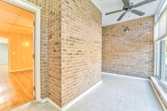 unfurnished sunroom featuring a drop ceiling and ceiling fan