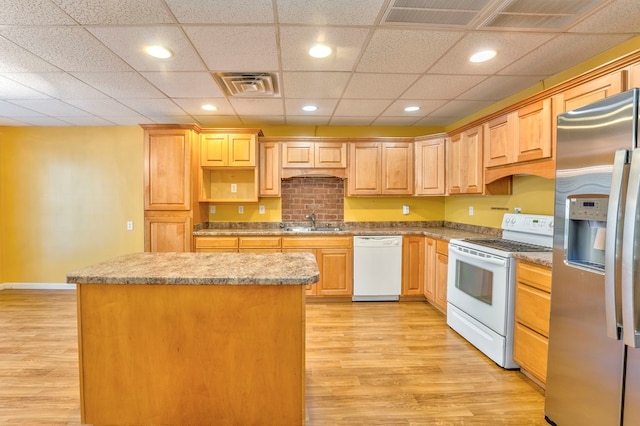 kitchen featuring a kitchen island, sink, white appliances, and light hardwood / wood-style floors