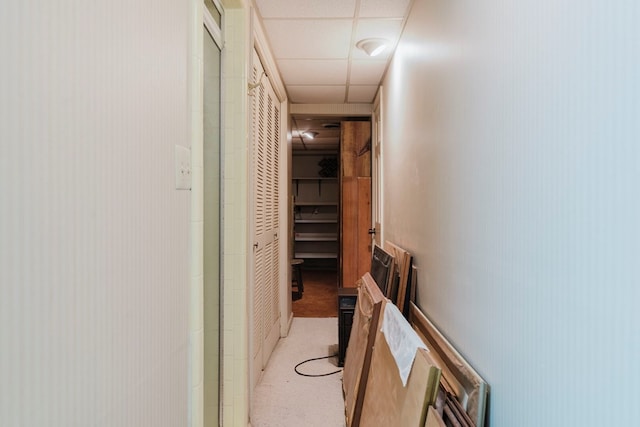 hallway with a paneled ceiling and light carpet