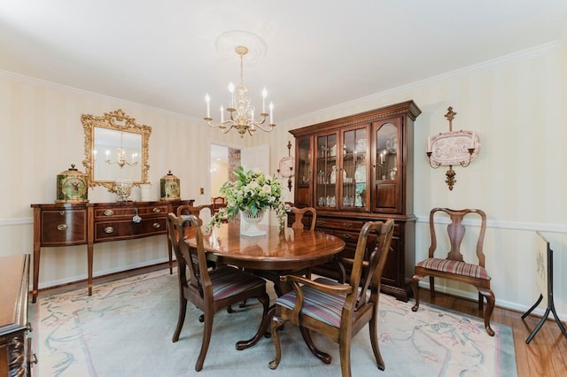 dining space with ornamental molding, an inviting chandelier, and light hardwood / wood-style floors